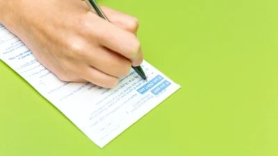 A person safely accessing practical guidance by writing on a piece of paper with a pen.