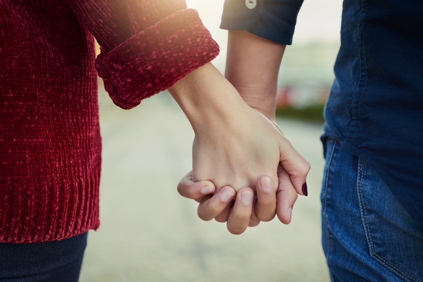 Two lovers holding hands in the street.