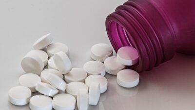 Takeda prescription drug savings pills falling out of a bottle on a white surface.