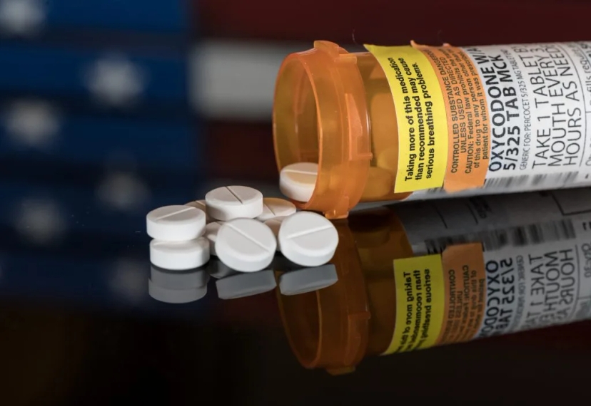 A bottle of Abbvie pills, representing prescription drug savings, placed prominently on top of an American flag.