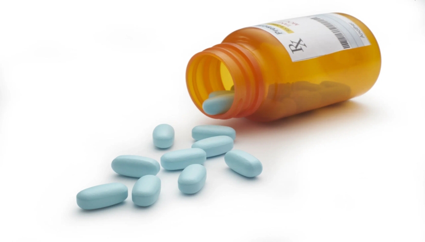 A pill bottle with blue pills spilling out of it, showcasing prescription drug savings.