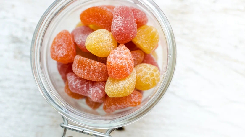 Effective gummy vitamins in a glass bowl on a wooden table.