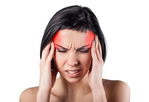 A woman experiencing migraines and the associated symptoms, holding her head due to the headache's intensity.