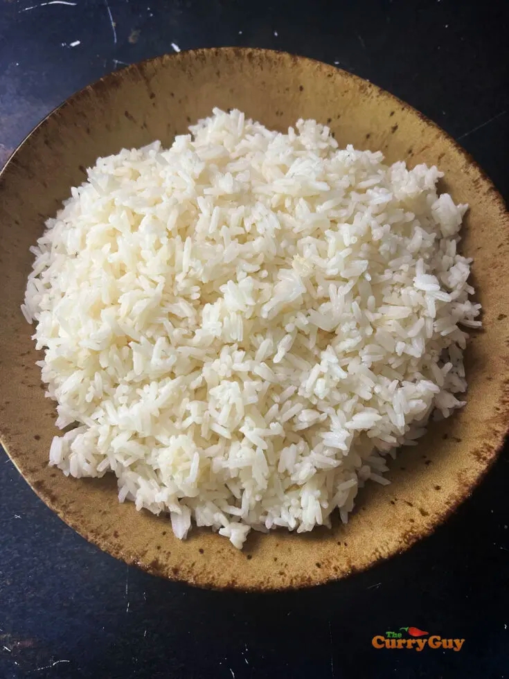 A bowl of rice, good for weight loss, on a dark surface.