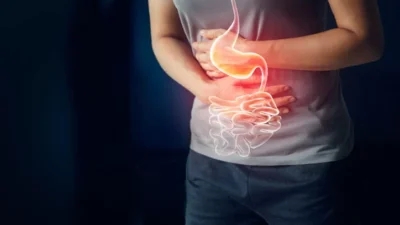A person holding their stomach area with a digital illustration of the digestive system, clearly showing upper stomach pain and discomfort.