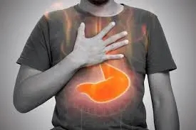 A person places a hand on their chest while a graphic of a stomach, illustrating how to stop acid reflux, is illuminated over their torso.