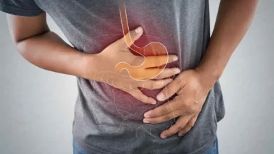 Person holding their stomach in pain, with a highlight on the digestive tract, representing symptoms of Crohn's disease.