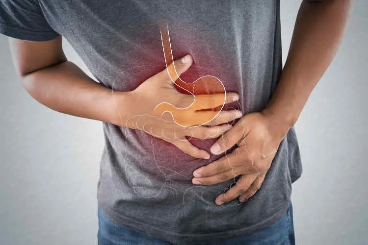 Person holding their stomach in pain, with a highlight on the digestive tract, representing symptoms of Crohn's disease.