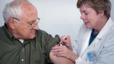 A healthcare professional administers an injection to an elderly man, illustrating medical treatment for unstable angina.