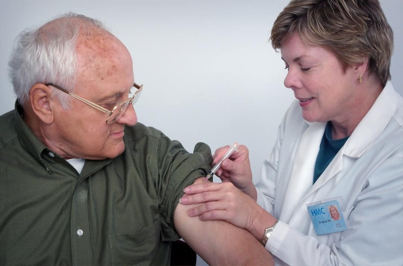 A healthcare professional administers an injection to an elderly man, illustrating medical treatment for unstable angina.