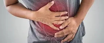 Person holding their stomach in discomfort, with a digestive tract area, representing constipation symptoms due to Crohn's disease.