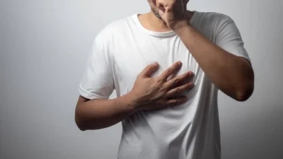 a man holding his chest in pain and coughing due to a chest infection