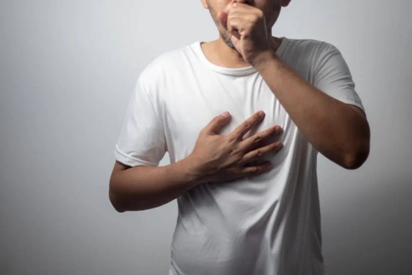 a man holding his chest in pain and coughing due to a chest infection