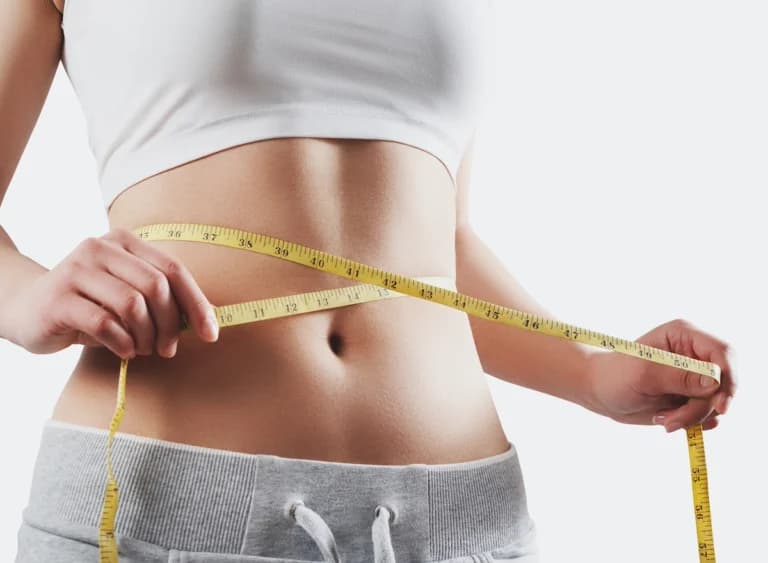 A woman is measuring her waist to track her progress while following an Intermittent Energy Restriction Diet.