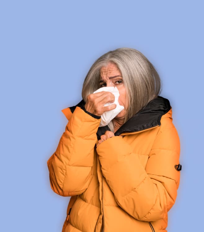 A woman in an orange jacket blowing her nose on a lavender background, representing NowPatient’s A-Z health conditions information directory