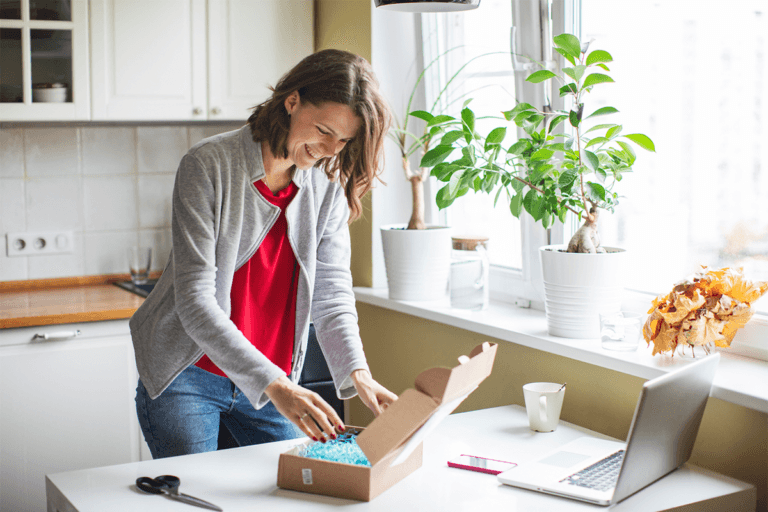 A NowPatient woman opening a box in her kitchen.