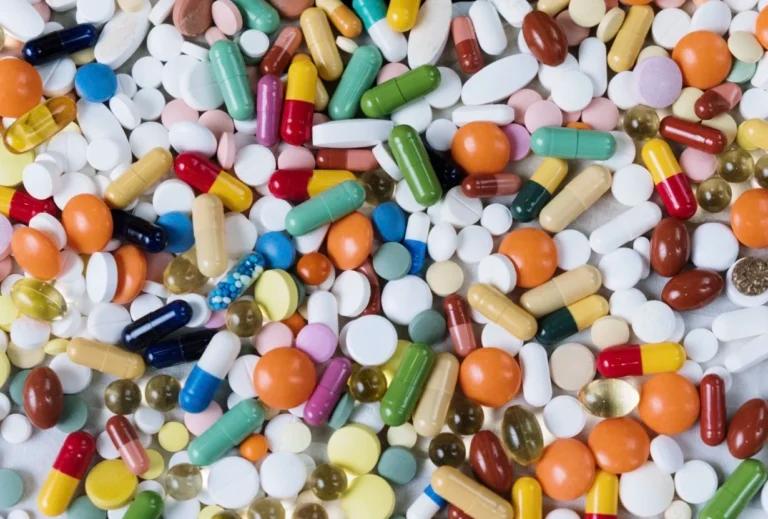 A collection of pills and capsules on a white surface, with free pill identifier tools available.