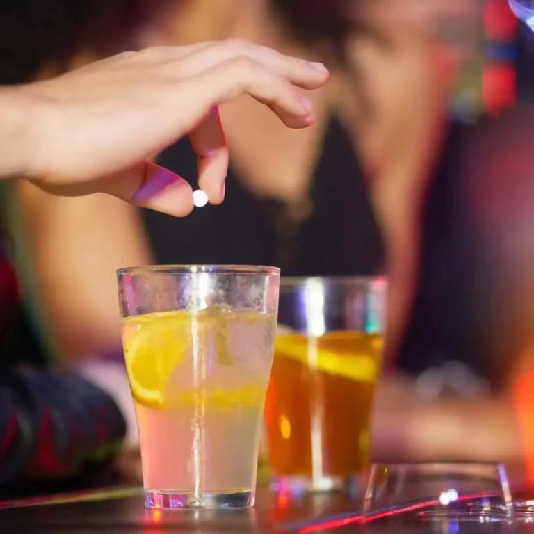 A person is pouring a drink into a glass, unaware of the potential risks of drink spiking.