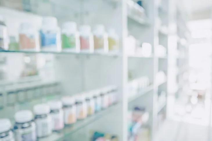 A blurry image of a pharmacy with shelves full of medication.