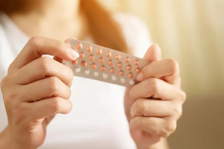 A woman holding a birth control pill in her hands.