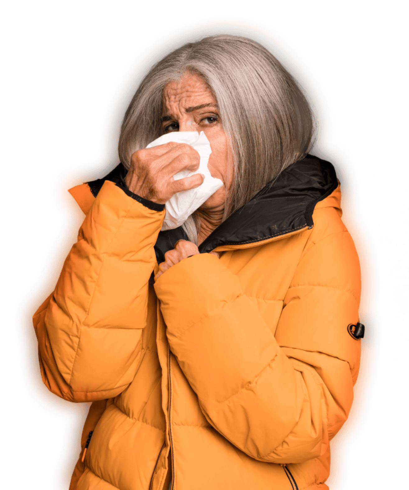 Elderly woman in an orange jacket holding a tissue to her nose, appearing to sneeze or blow her nose.