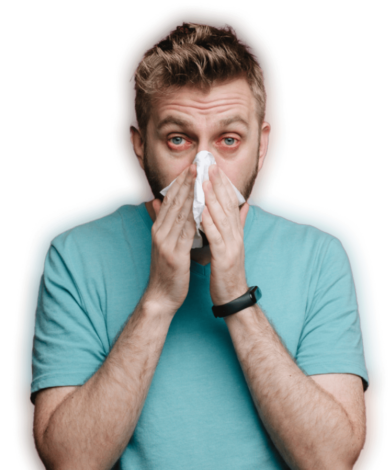 A man in a blue T-shirt with red eyes blows his nose into a tissue.