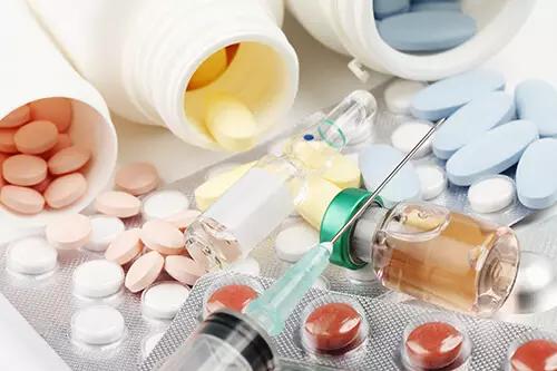 Various pills, tablets, and a syringe looking at the potential link between drug use and schizophrenia.
