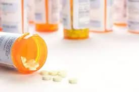 A group of prescription drugs are spilling out of a bottle labeled Pfizer.
