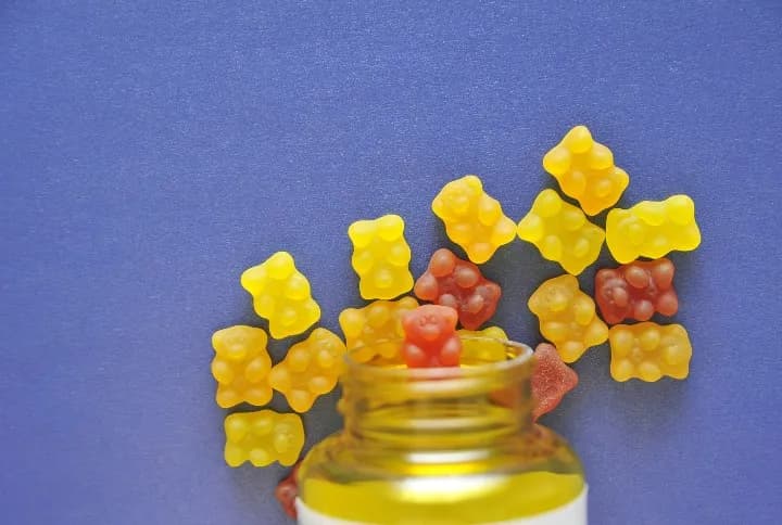 A bottle of gummy bears on a blue background.
