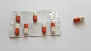 A blister pack with seven red and white capsules, with one capsule placed outside the pack on a white background. It's essential to note pregabalin interactions and contraindications before use.