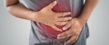 Person holding their stomach in discomfort, with a digestive tract area, representing constipation symptoms due to Crohn's disease.