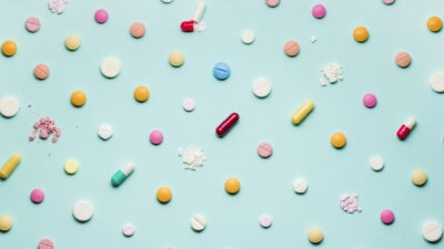 Colorful pills and capsules combating antibiotic resistance on a blue background.