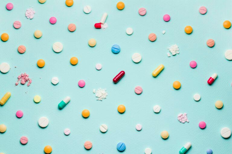 Colorful pills and capsules combating antibiotic resistance on a blue background.
