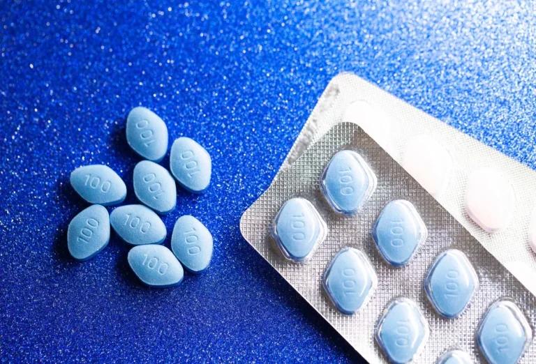 A pack of viagra pills on a blue surface.