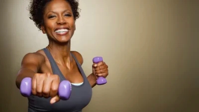 A woman showcasing the 7 best workouts with purple dumbbells for weight loss in a photo.