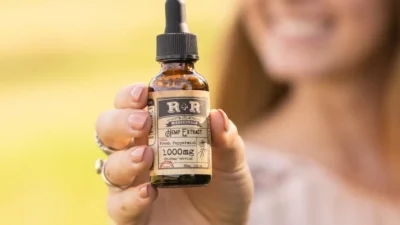 A woman holding up a small bottle of CBD oil for anxiety.