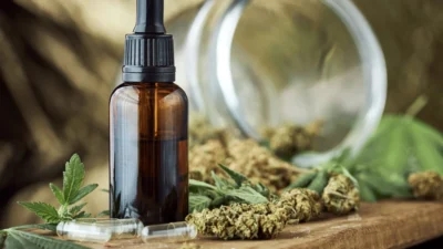 Cbd oil and cannabis leaves on a wooden table, beneficial for nausea.
