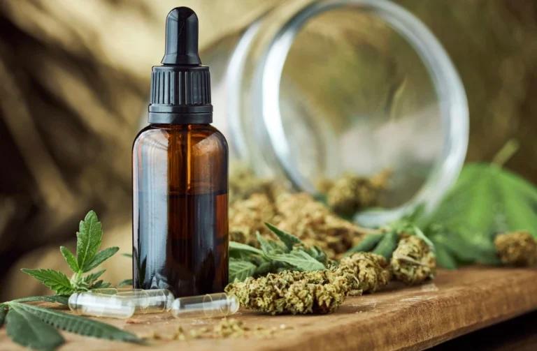 Cbd oil and cannabis leaves on a wooden table, beneficial for nausea.
