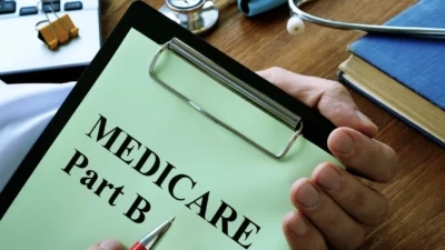 Costs and coverage of Medicare Part B depicted on a hand holding a clipboard.