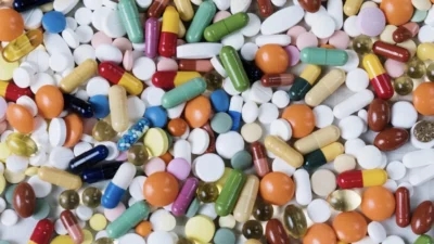 A collection of pills and capsules on a white surface, with free pill identifier tools available.