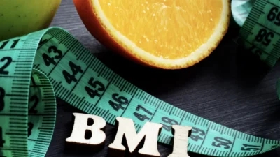 A measuring tape with the word BMI next to an apple.