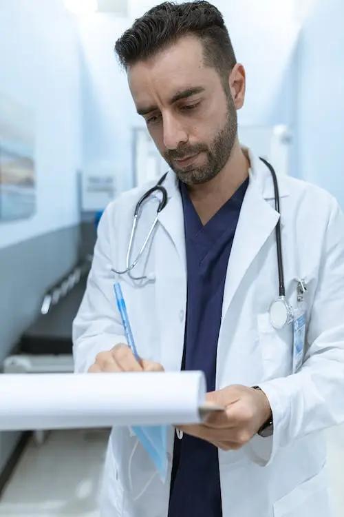 A male doctor in a hospital holding a clipboard providing Medicare advice for those still working.