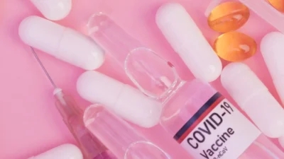 Syringes filled with vitamins and Wegovy pills on a pink background.