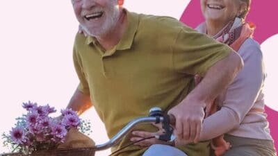 An older couple riding a bicycle with flowers in a Blue Zone state.