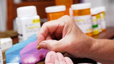 A person is carefully packaging Amneal prescription drugs into a box, ensuring maximum prescription drug savings for customers.