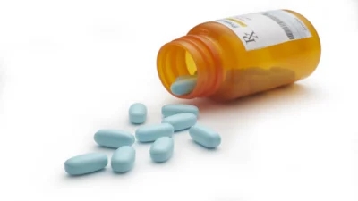 A pill bottle with blue pills spilling out of it, showcasing prescription drug savings.