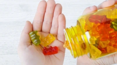 A person's hand holding a jar of gummy bears, possibly for work purposes.