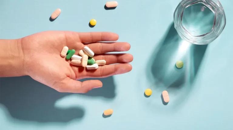 An emergency supply of medication, showcased by a hand holding pills and a glass on a blue background.