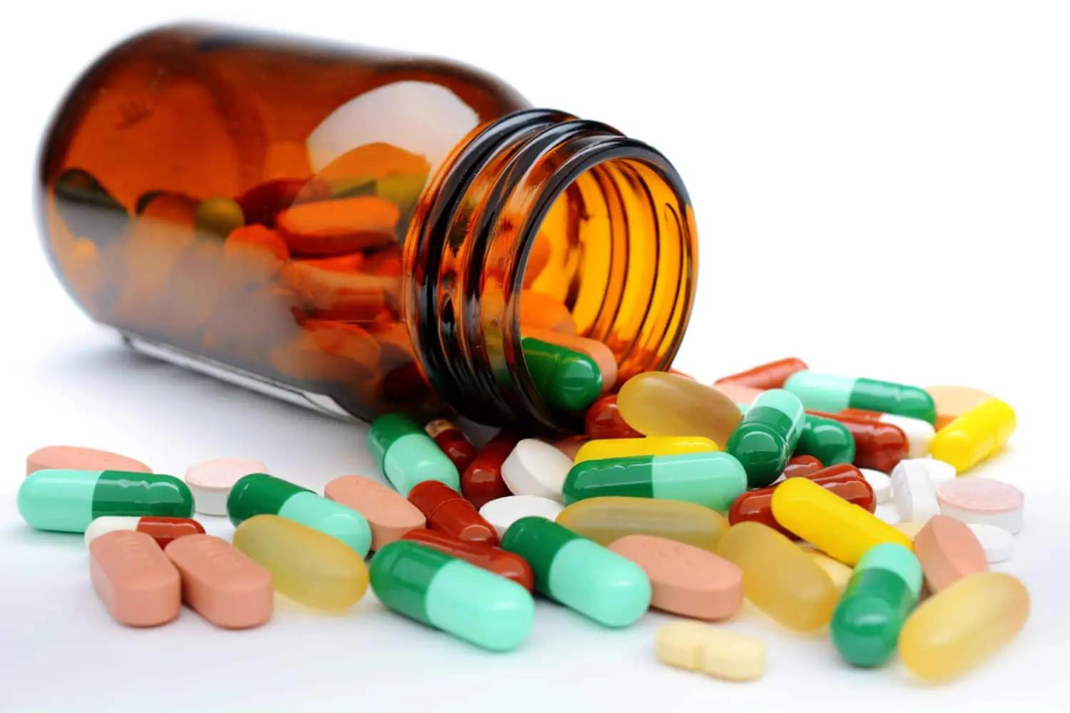 A bottle of medication pills spilling out onto a white background.