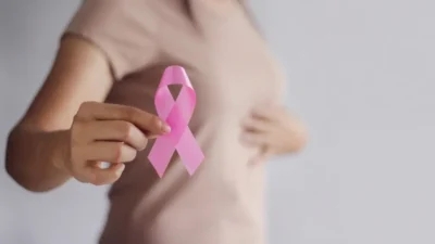 A woman holding a pink ribbon in her hand as a symbol of support for the fight against breast cancers.